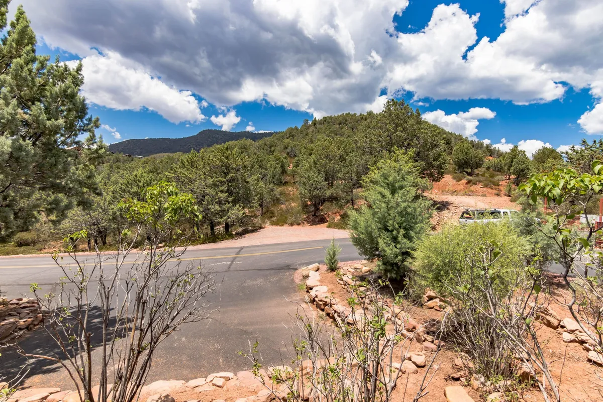 A sweeping exterior vista featuring mountains, vibrant greenery, and a road leading into the scenic distance. The sky is tinged with hues suggestive of a sunset, highlighting the beauty of the surrounding Mogollon Rim and the peaceful atmosphere perfect for couples.